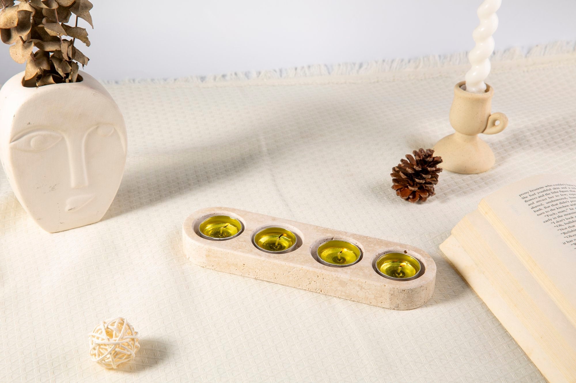 Koville natural marble tea light candle holder 4 holes in Travertino Romano with a lit tea light candle
