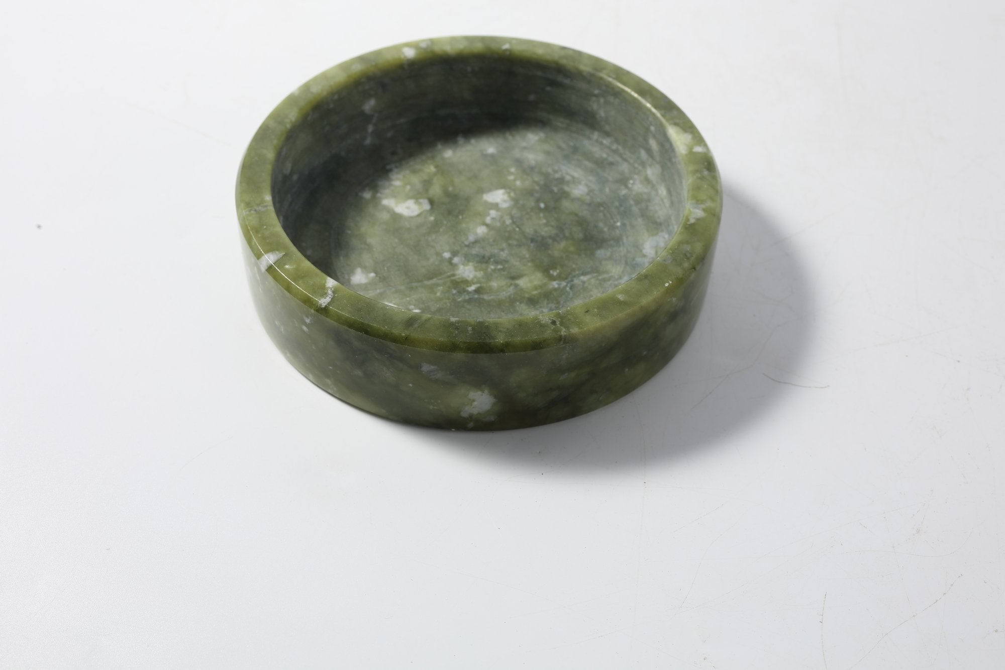 Koville Natural Stone Wine Bottle Holder in Dandong Green on a dining table holding a wine bottle