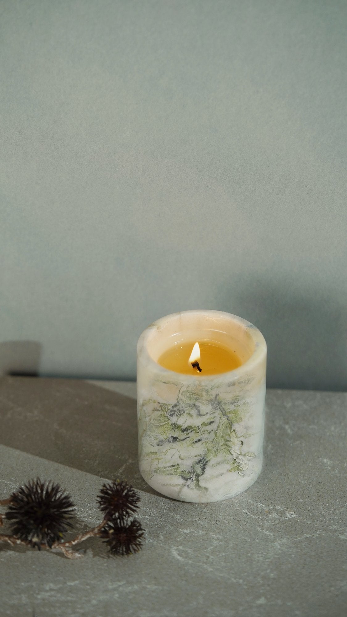 Koville natural marble scented candle d 110 in Bianco Palomino with a lit tea light candle
