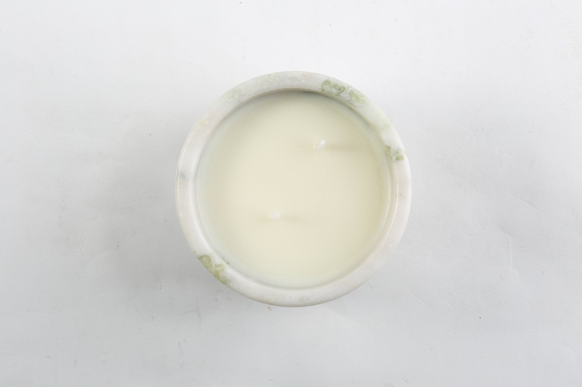 Koville natural marble scented candle d 110 in Bianco Palomino with a lit tea light candle