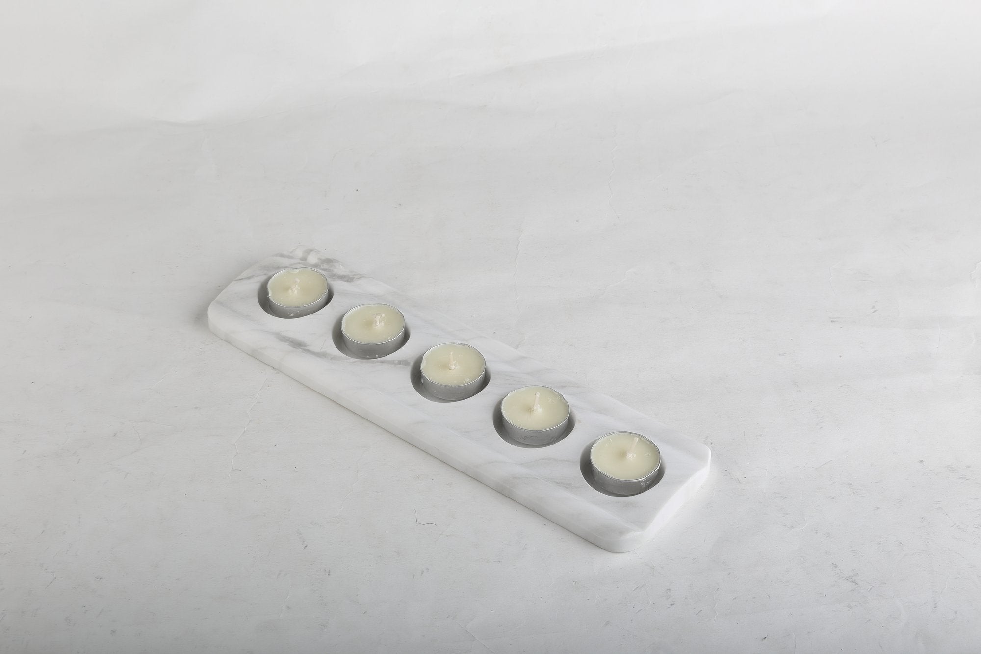 Koville natural marble tea light candle holder 5 holes in Namib Bianco with a lit tea light candle